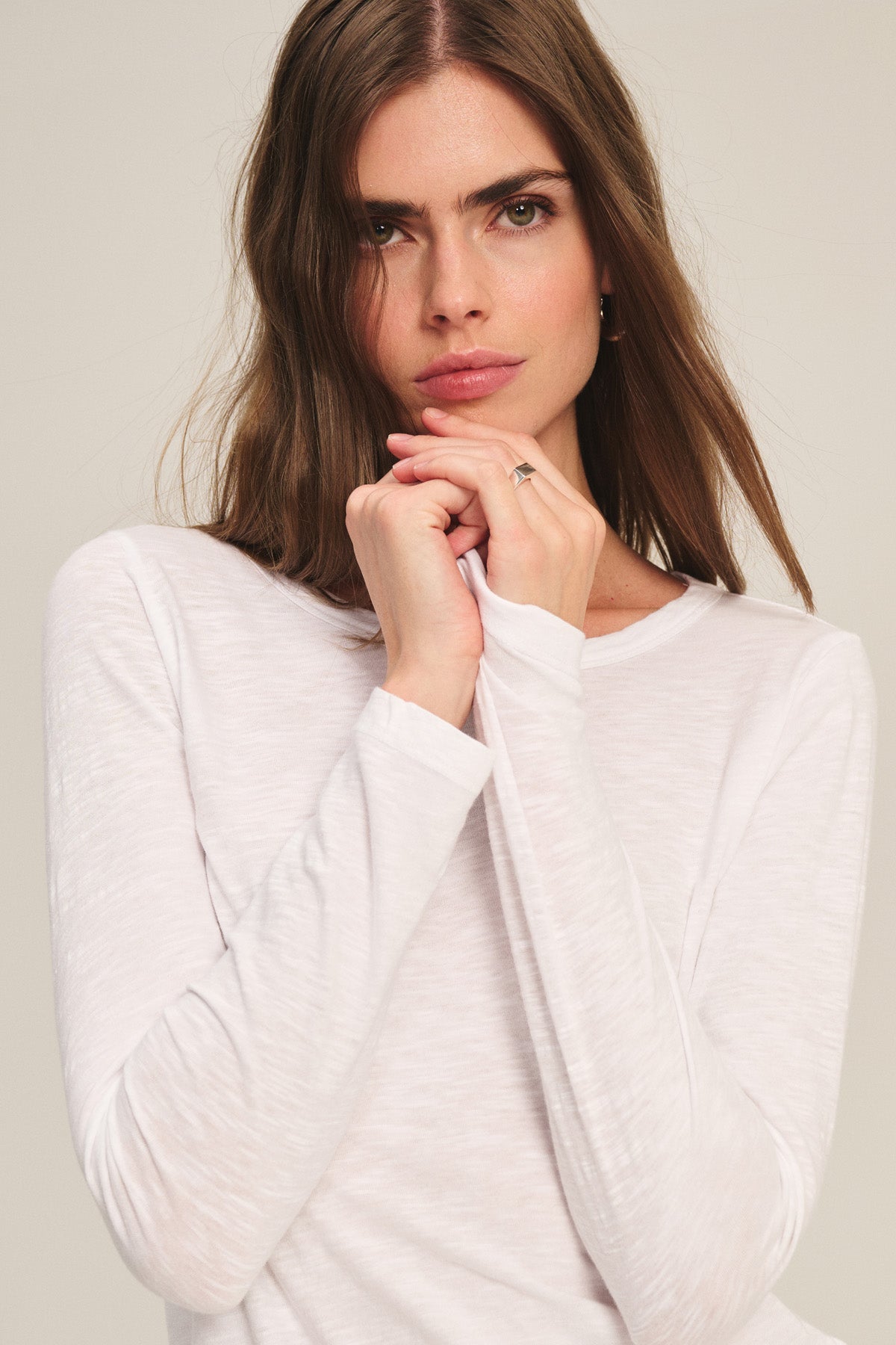 A woman with long brown hair models the LIZZIE TEE by Velvet by Graham & Spencer, posing with her hands near her face against a plain background.-40305606951105