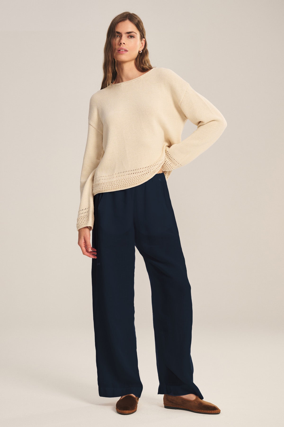 Person standing against a plain background, wearing a beige knit sweater, brown loafers, and the LOLA LINEN PANT by Velvet by Graham & Spencer—navy pull-on trousers with an elastic waist.-41073344708801