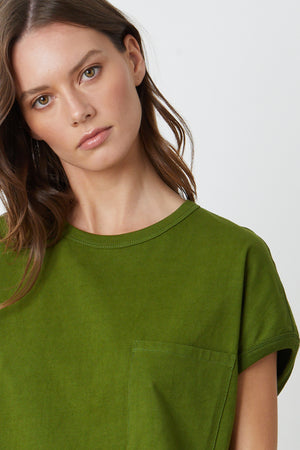 The model is wearing a green Cassidy Crew Neck Dress with a pocket by Velvet by Graham & Spencer.