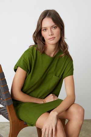 the model is sitting on a wooden chair in a Velvet by Graham & Spencer CASSIDY CREW NECK DRESS.