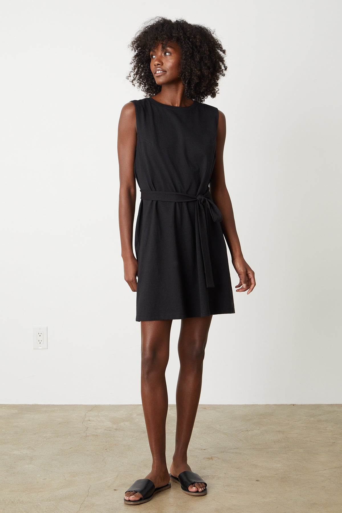 A woman wearing a black LAINE STRUCTURED TANK DRESS by Velvet by Graham & Spencer with a belt.-26342718570689