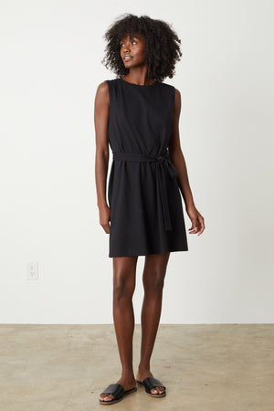 A woman wearing a black LAINE STRUCTURED TANK DRESS by Velvet by Graham & Spencer with a belt.