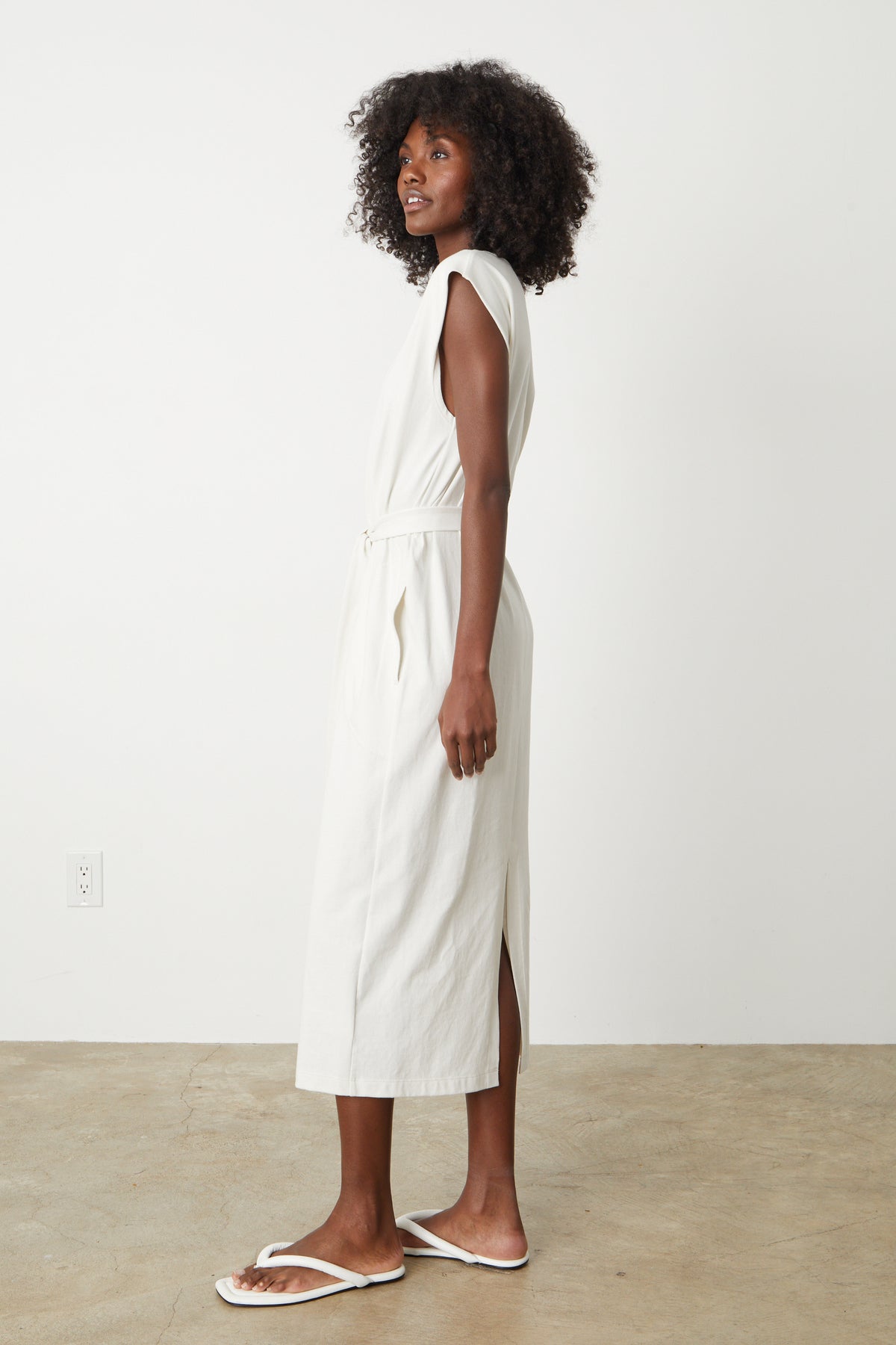 A woman wearing a white MACI SCOOP NECK DRESS by Velvet by Graham & Spencer and flip flops.-26559900352705