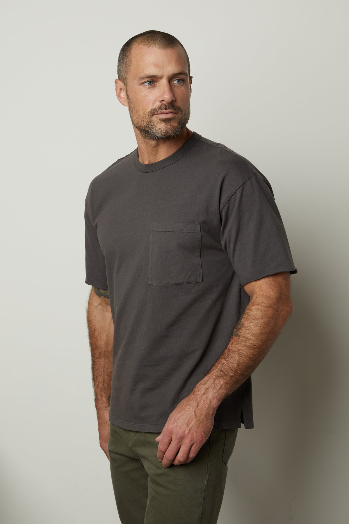   A man wearing a NEPTUNE CREW NECK POCKET TEE by Velvet by Graham & Spencer and green pants. 