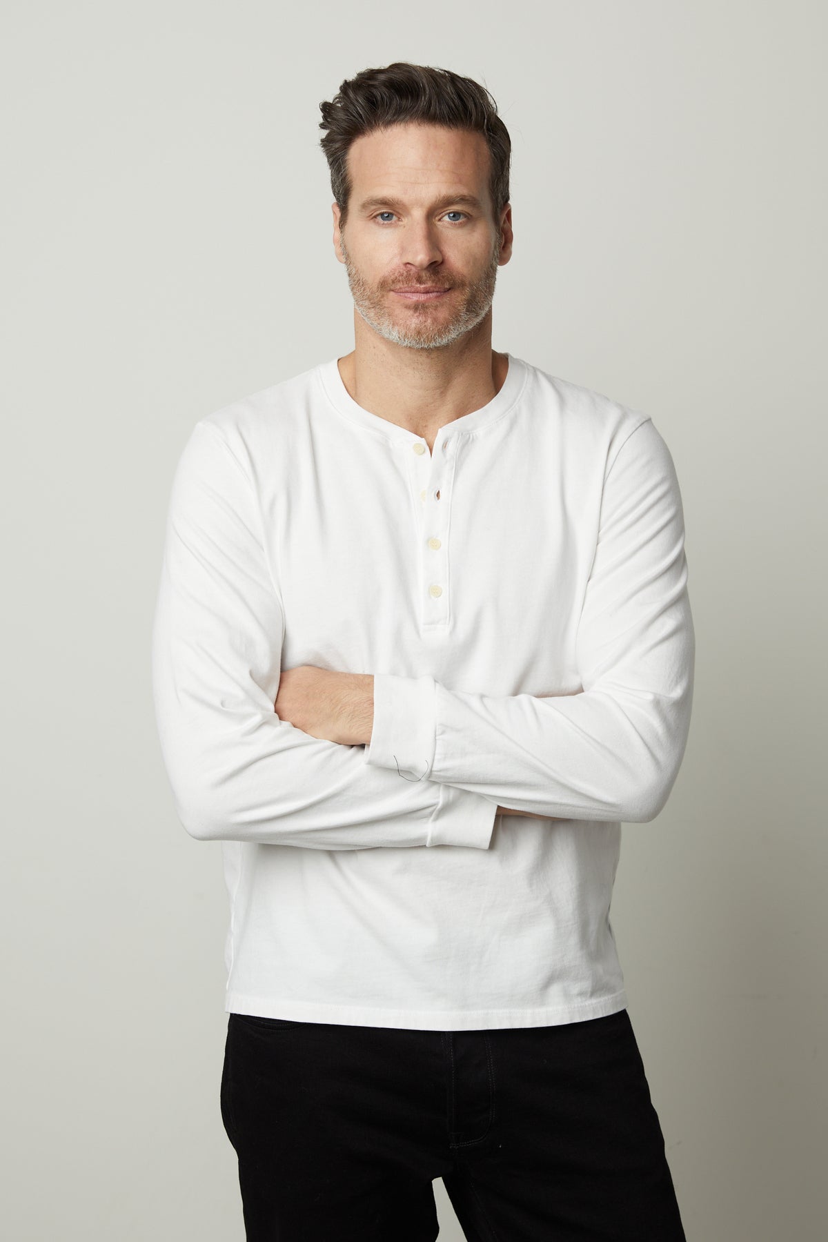   A man wearing a white REMI HENLEY t - shirt by Velvet by Graham & Spencer. 