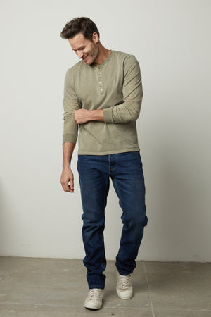 A man wearing REMI HENLEY jeans and a long-sleeved shirt by Velvet by Graham & Spencer.
