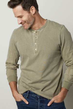 A man wearing jeans and a green Velvet by Graham & Spencer REMI HENLEY shirt.