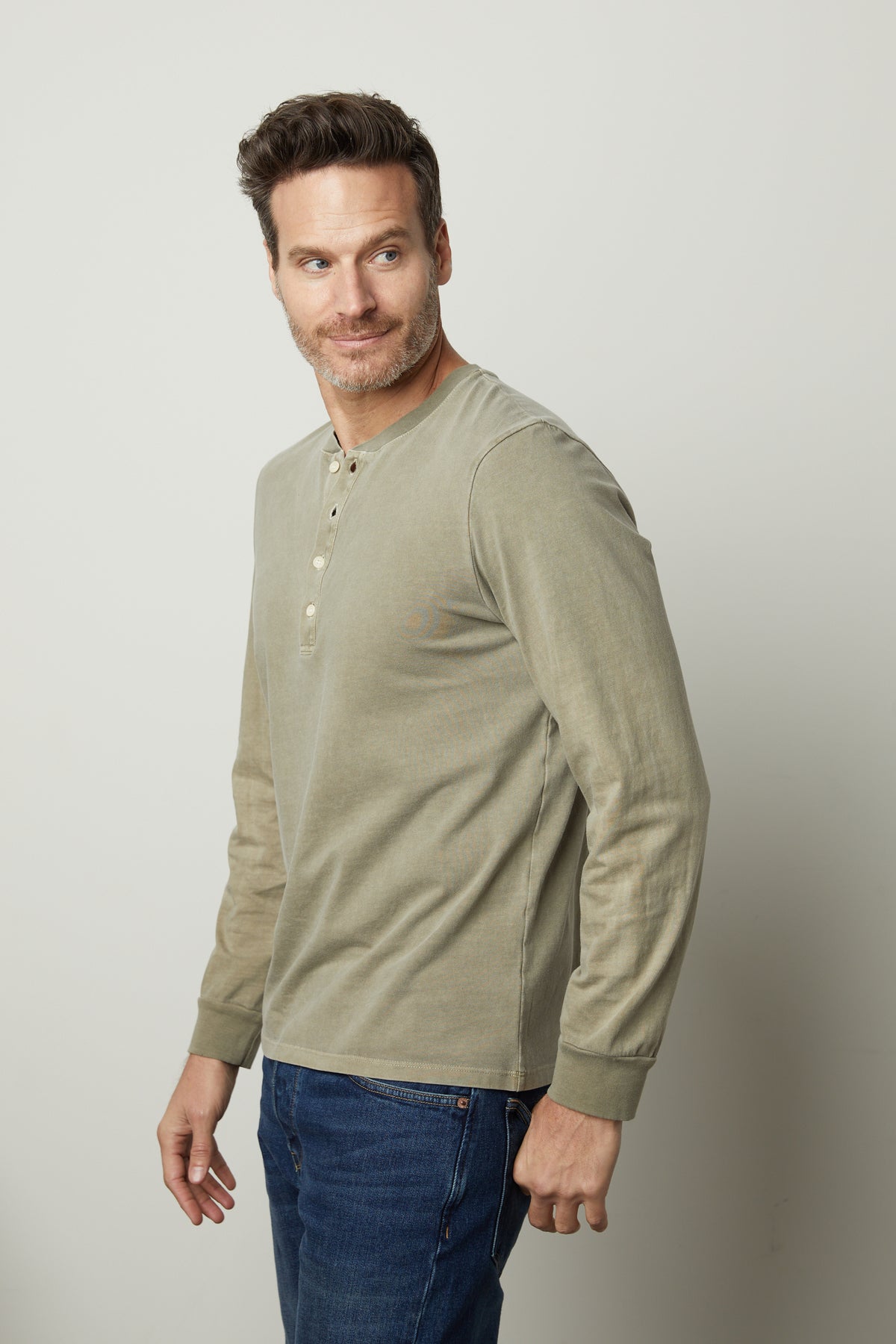   A man in jeans and a green Velvet by Graham & Spencer REMI HENLEY shirt. 
