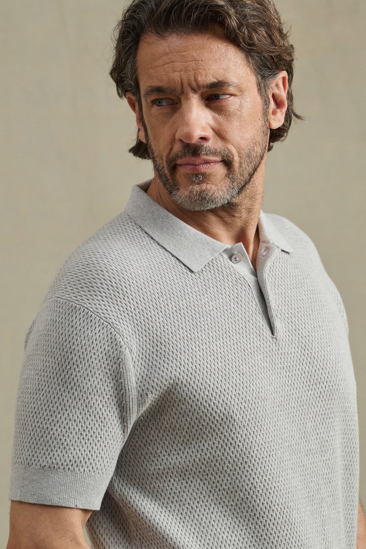 A man with short brown hair and a beard wears the LOWELL SWEATER POLO by Velvet by Graham & Spencer in light gray, standing against a plain neutral background.
