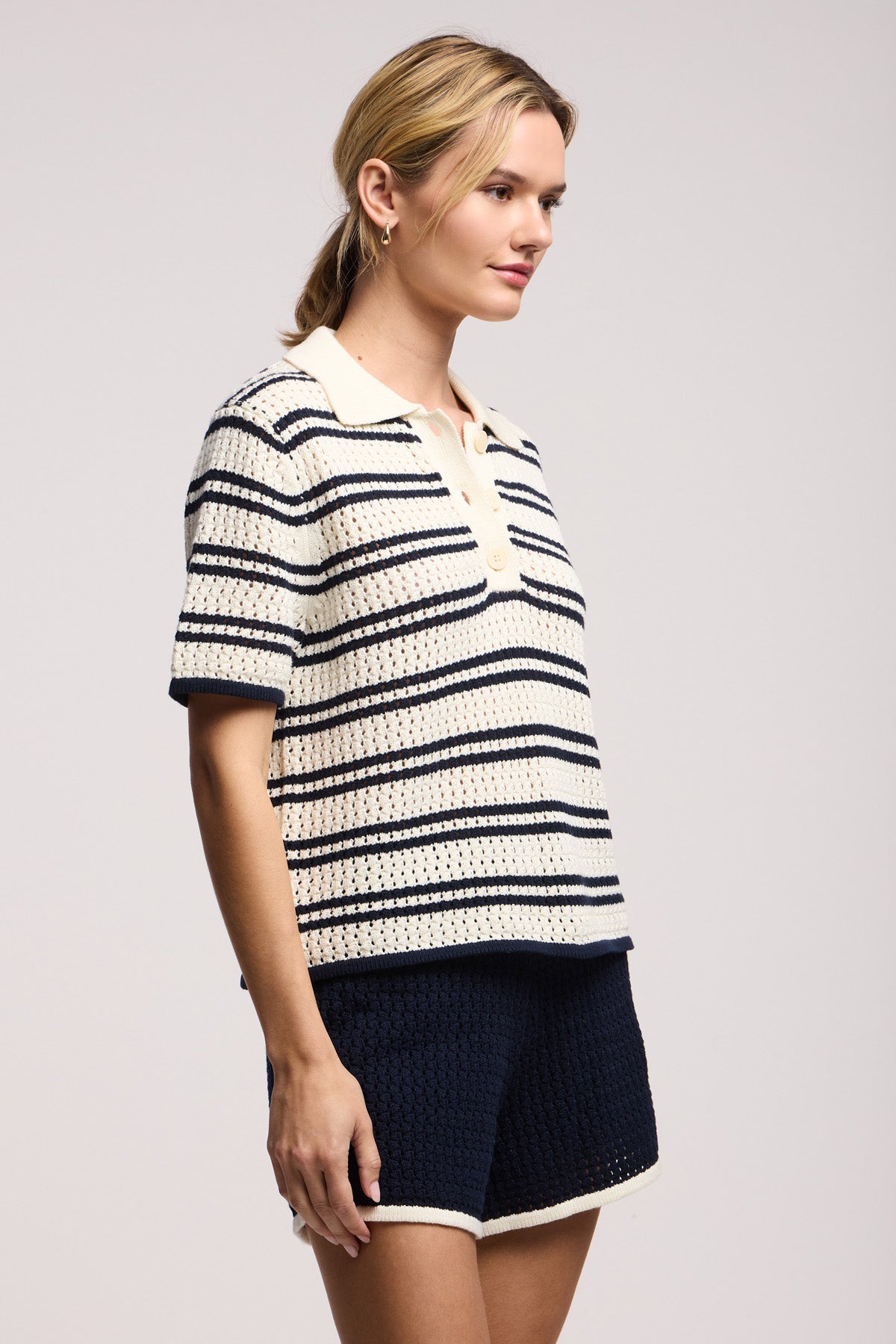 A woman wears Velvet by Graham & Spencer’s JENIFER SHORT—navy lounge shorts with an elastic waist—paired with a cream and navy striped short-sleeve knit polo shirt, standing against a plain background.-41371945664705