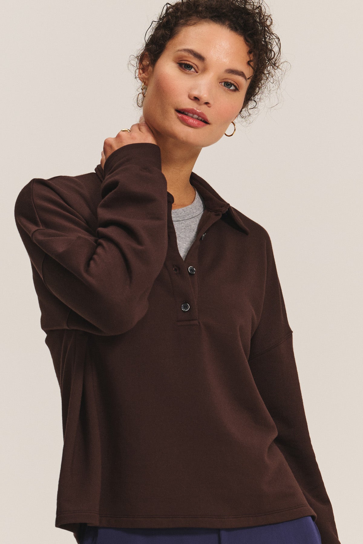 A woman models the MARIAN SWEATSHIRT by Velvet by Graham & Spencer—a dark brown, collared style layered over a gray top—standing against a light background and looking at the camera.