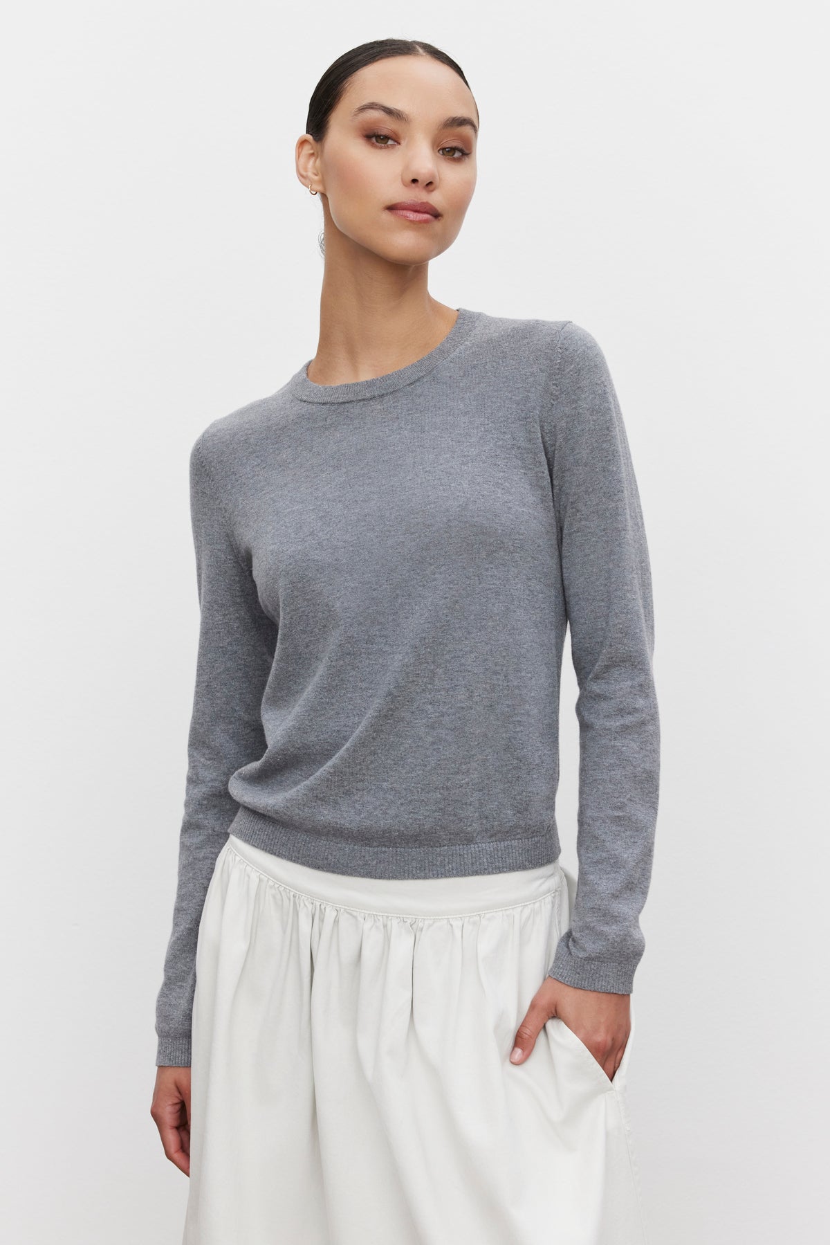   Person wearing a ROXY SWEATER by Velvet by Graham & Spencer, styled with a white skirt and standing against a plain white background. 