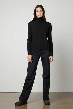 The model is wearing a Velvet by Graham & Spencer SALLY MOCK NECK SWEATER in a cotton-cashmere blend.