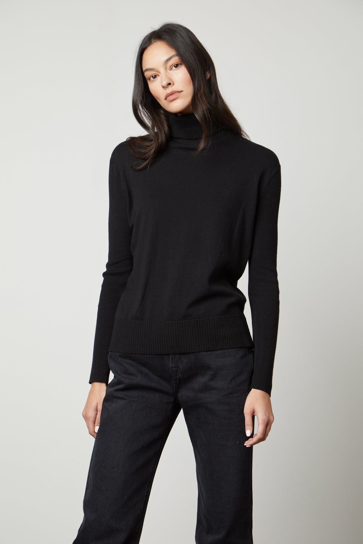   A woman wearing a Velvet by Graham & Spencer Sally Mock Neck Sweater and black jeans. 