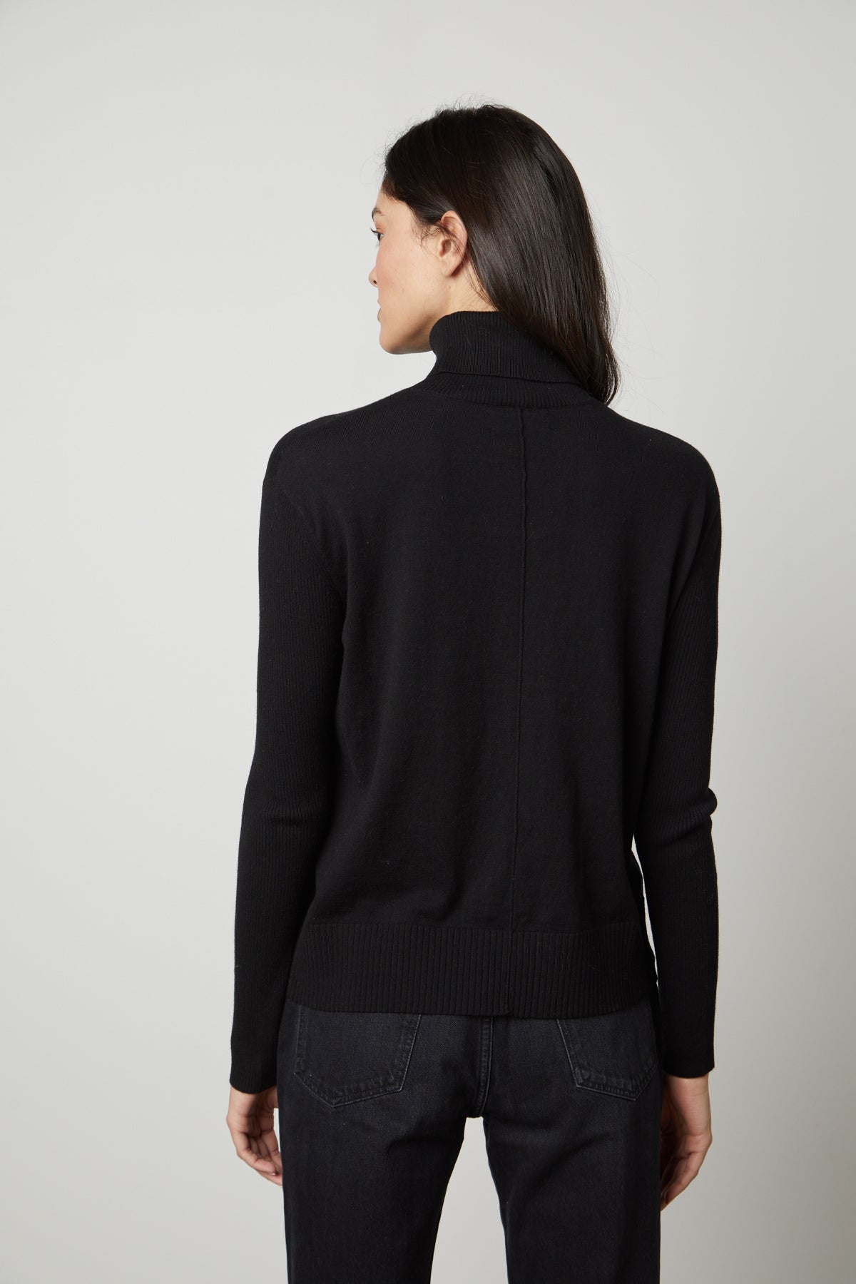The back view of a woman wearing a fitted black SALLY MOCK NECK SWEATER from Velvet by Graham & Spencer.-26910281466049