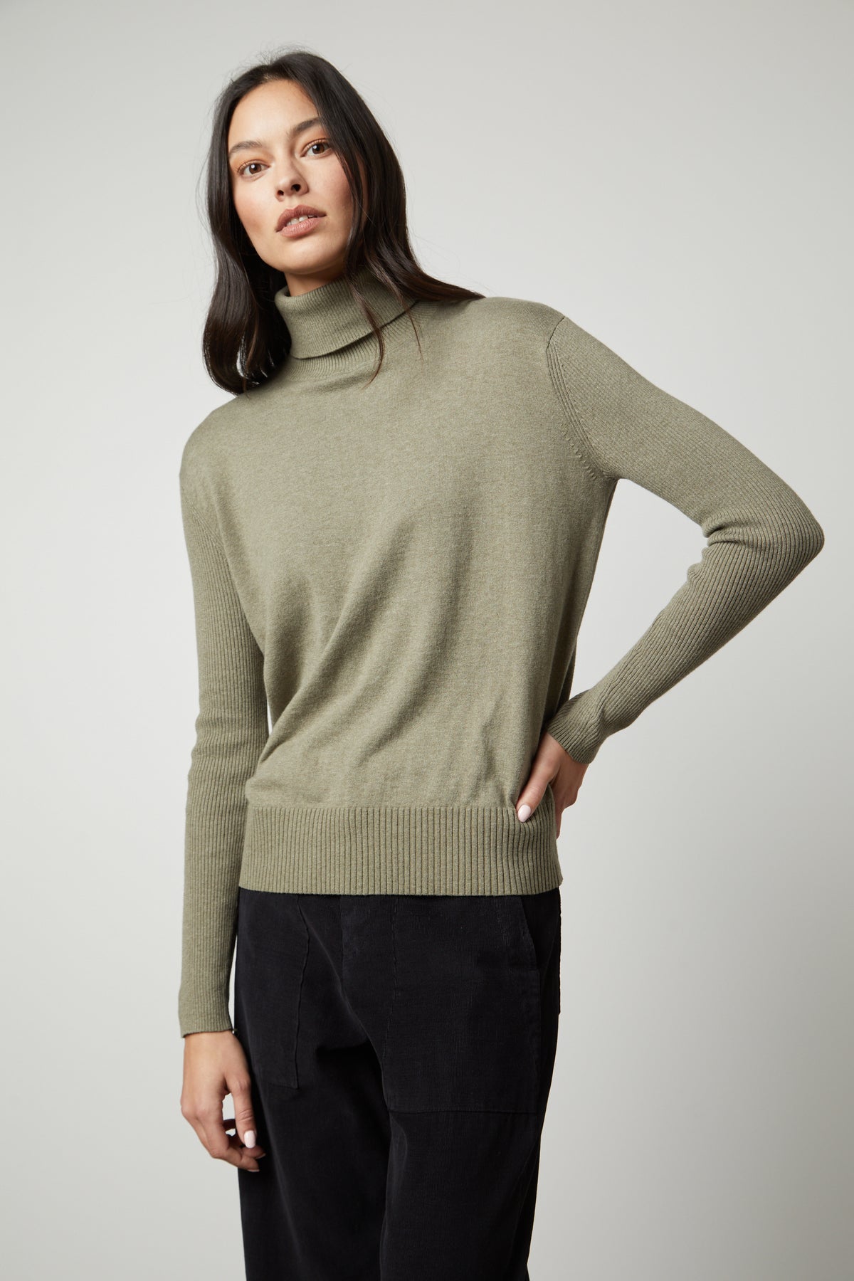 The model is wearing a ribbed green SALLY MOCK NECK SWEATER by Velvet by Graham & Spencer.-35503515926721