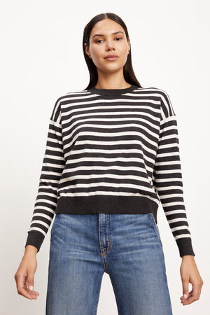 The model is wearing a warm Velvet by Graham & Spencer black and white Alister striped crew neck sweater with a cozy texture.