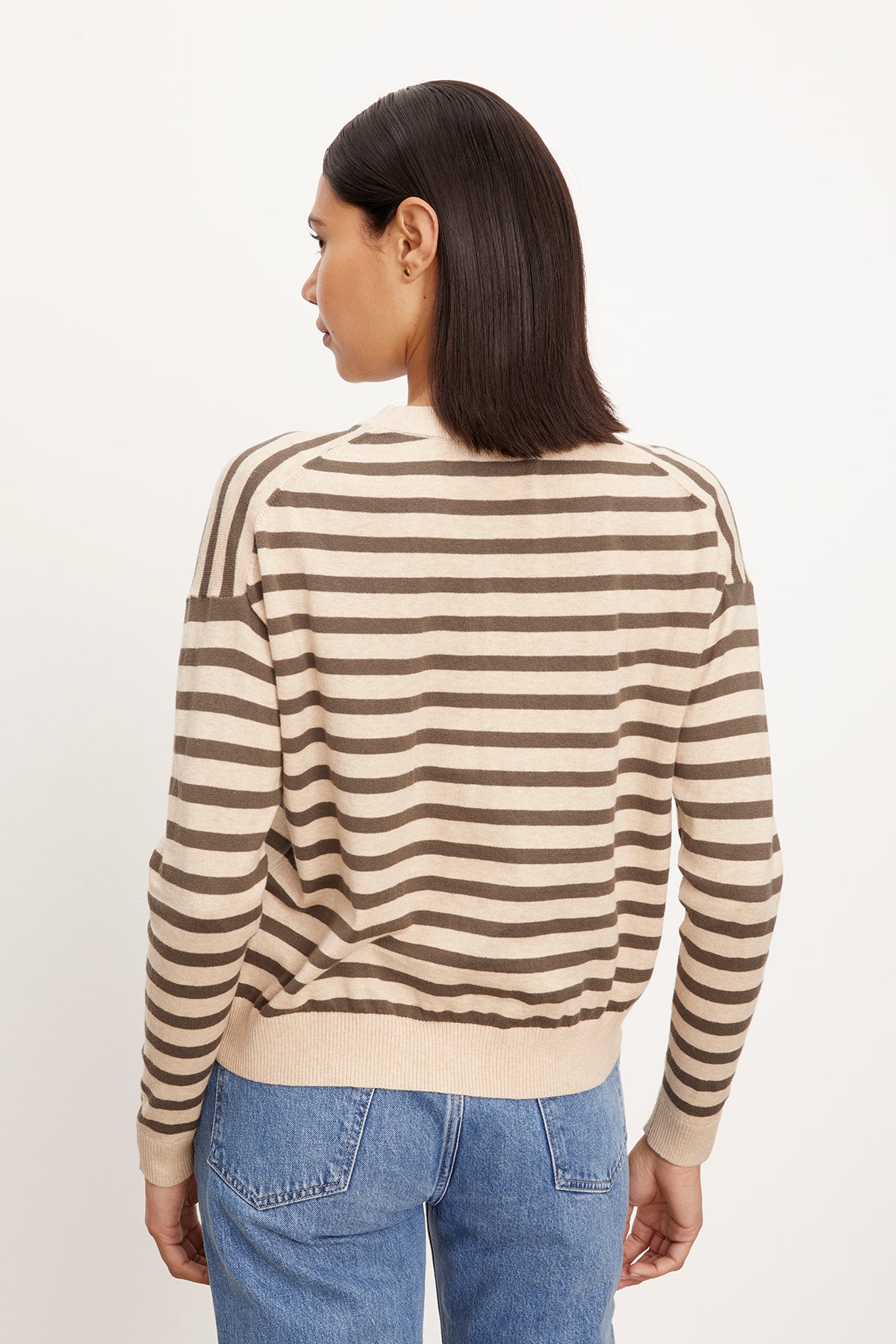  The back view of a woman wearing the Velvet by Graham & Spencer ALISTER STRIPED CREW NECK SWEATER and jeans. 