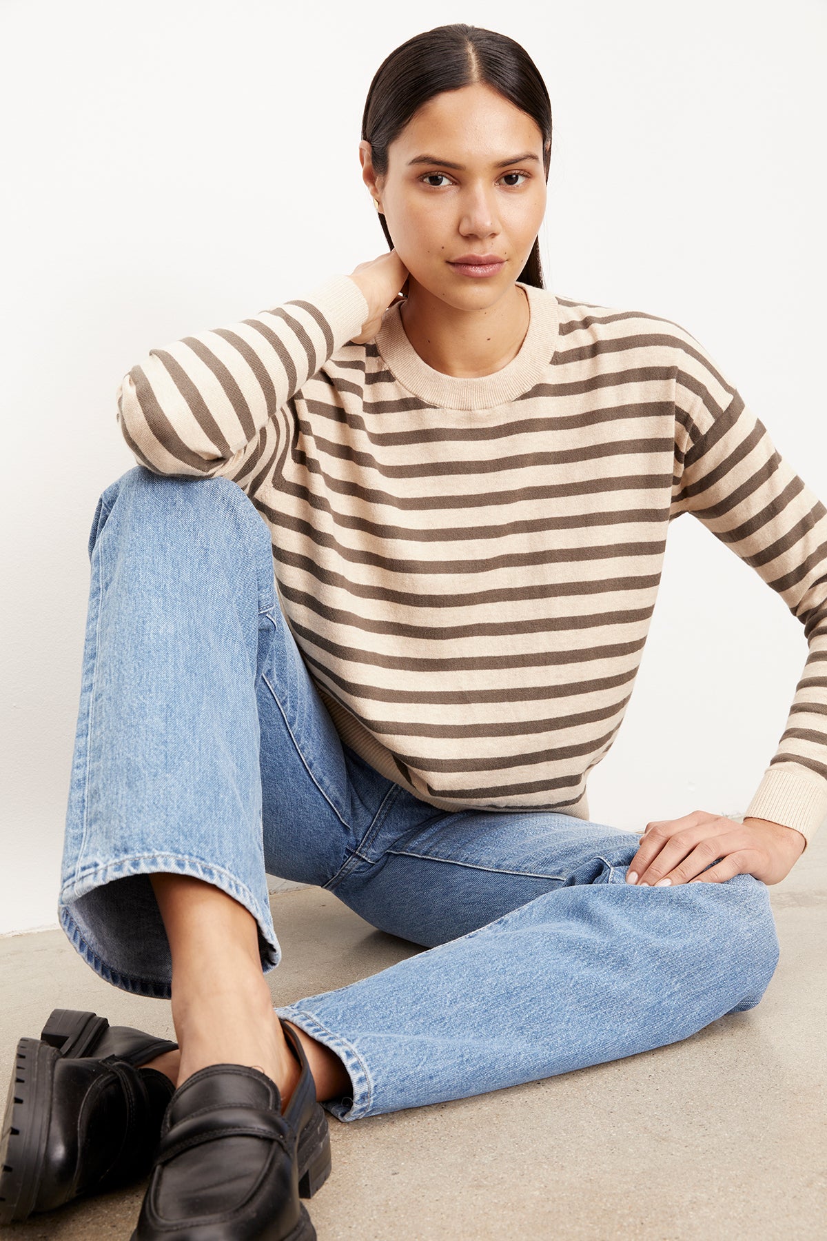   The model is wearing a Velvet by Graham & Spencer ALISTER STRIPED CREW NECK SWEATER and jeans. 