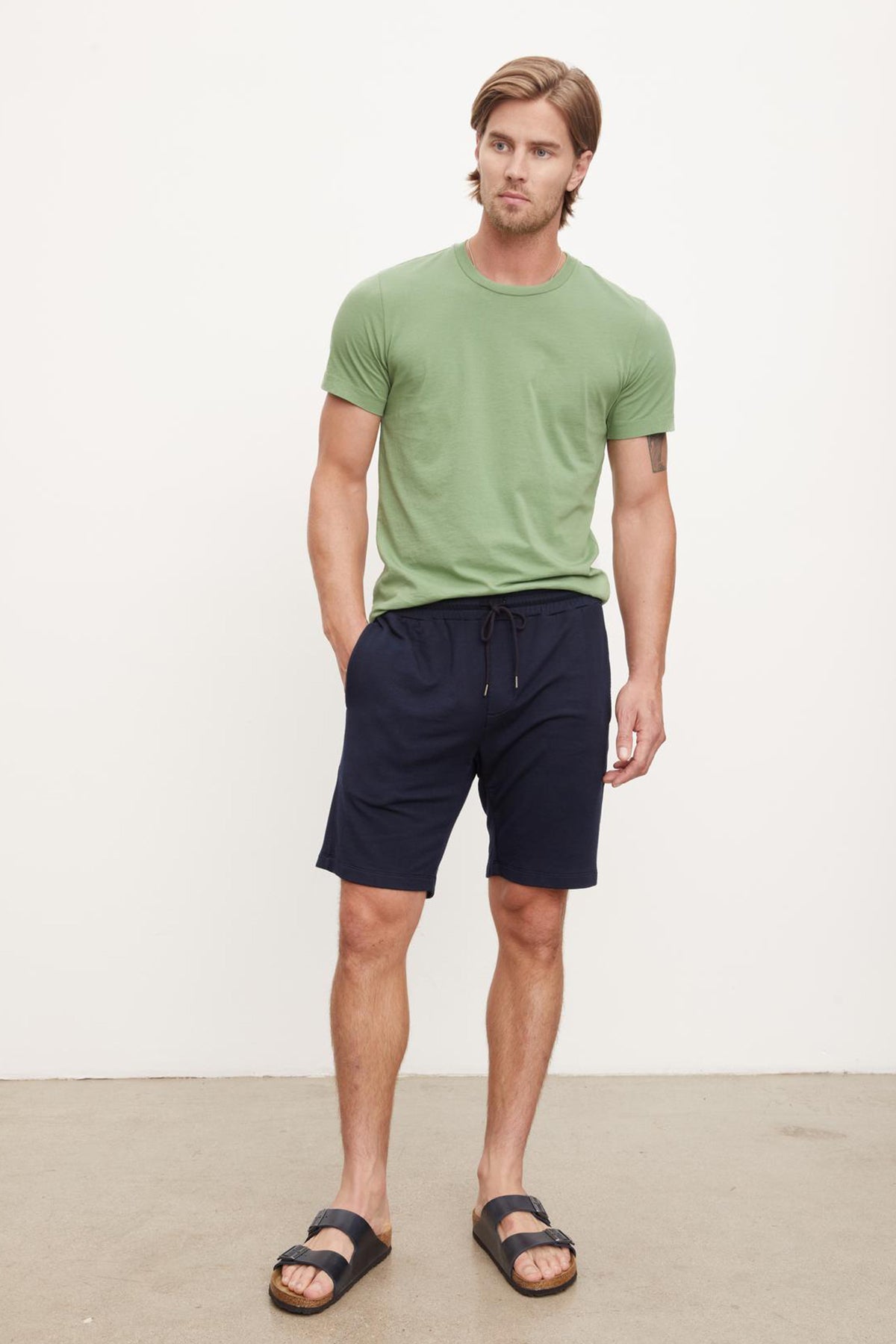   The model is wearing a cozy green t-shirt and Velvet by Graham & Spencer ATLAS LUXE FLEECE DRAWSTRING SHORT. 