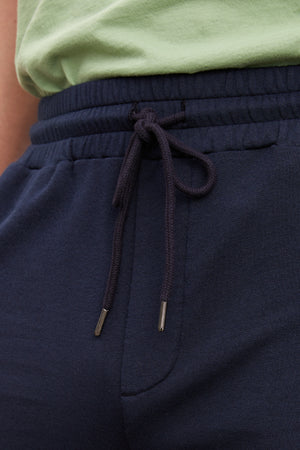 A close up of a man wearing Velvet by Graham & Spencer ATLAS LUXE FLEECE DRAWSTRING SHORT, perfect for workouts and providing a cozy interior.