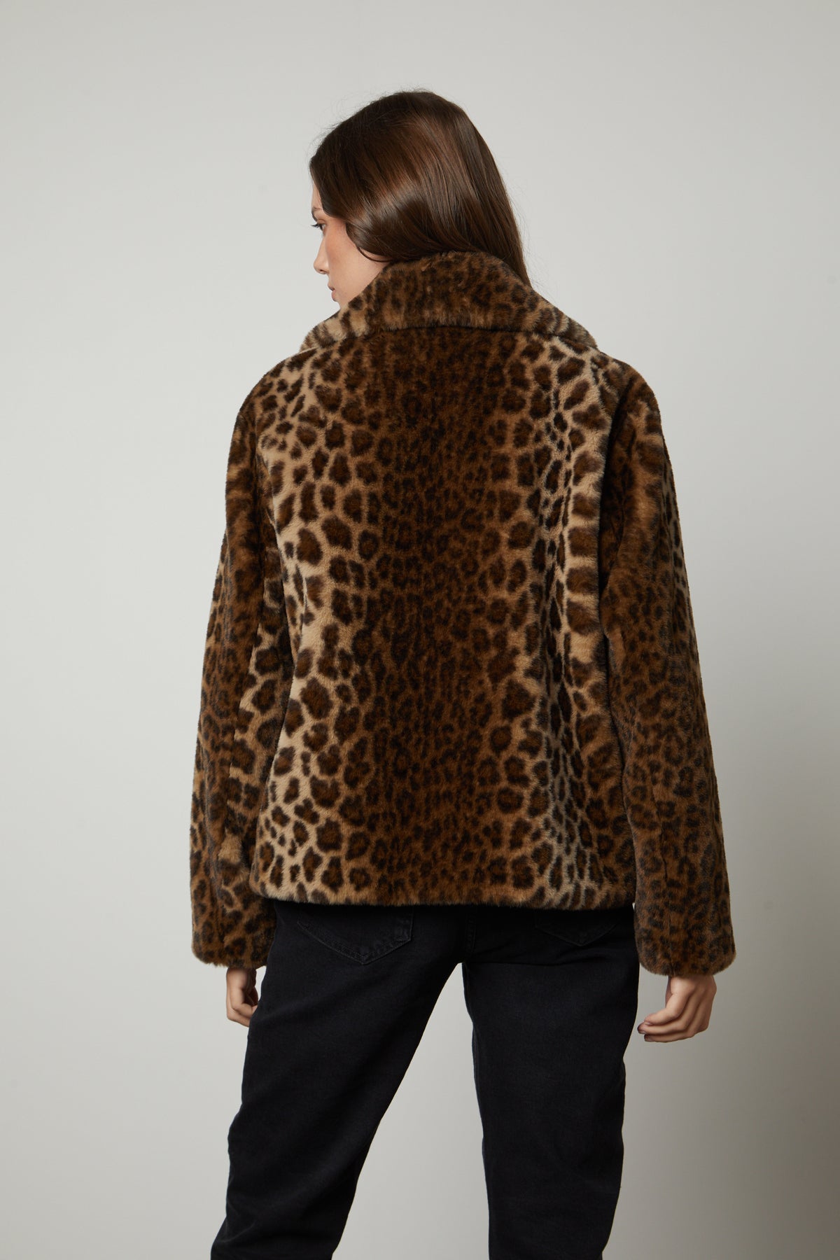   The back view of a woman wearing a Velvet by Graham & Spencer AMANI LEOPARD LUX FAUX FUR JACKET. 
