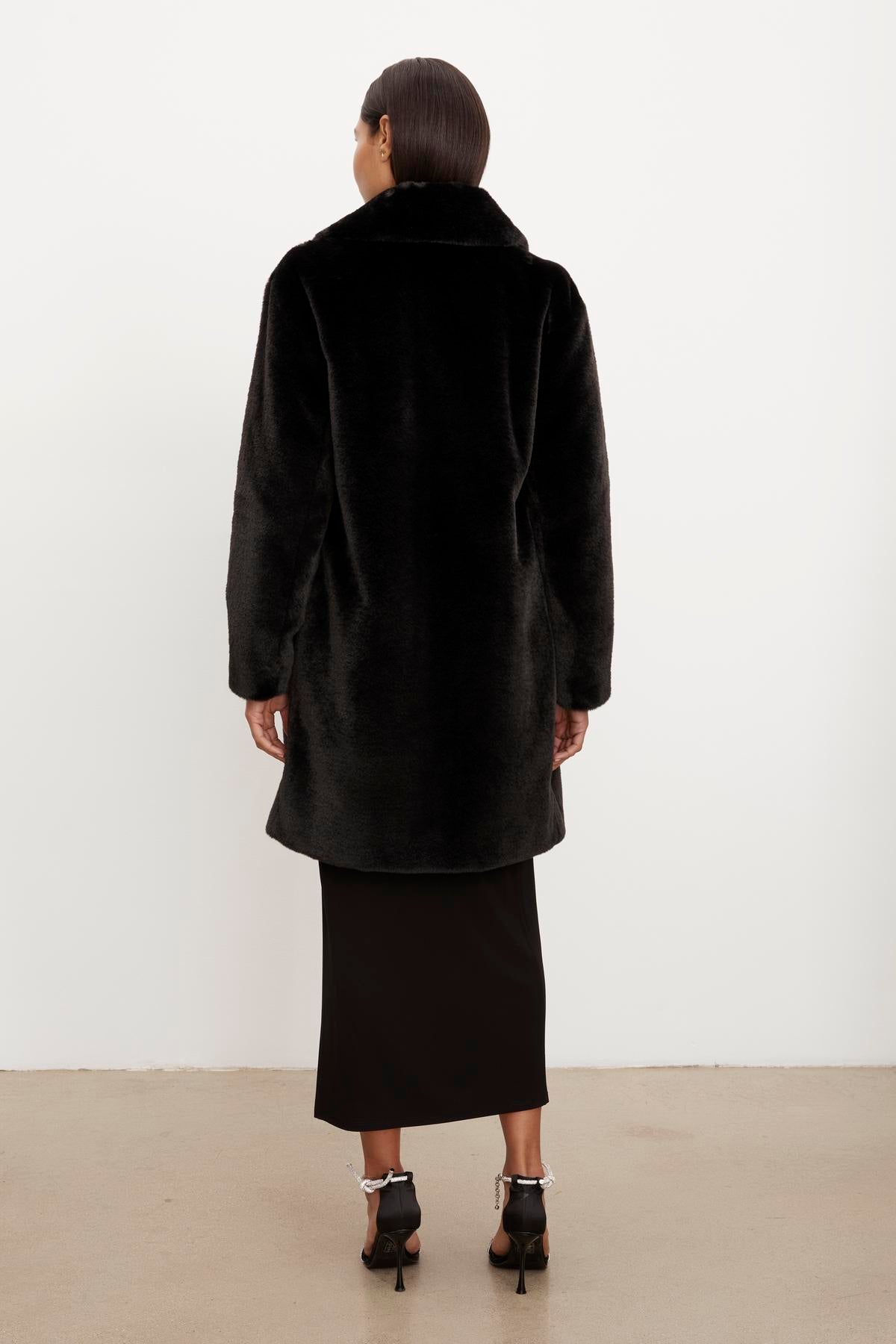The silhouette of a woman wearing an EVALYN LUX FAUX FUR COAT by Velvet by Graham & Spencer.-35624035320001