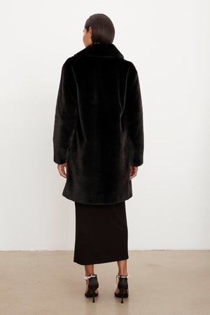 The silhouette of a woman wearing an EVALYN LUX FAUX FUR COAT by Velvet by Graham & Spencer.