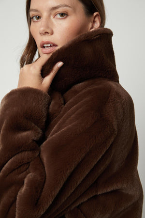 A model wearing a Velvet by Graham & Spencer EVALYN LUX FAUX FUR COAT.