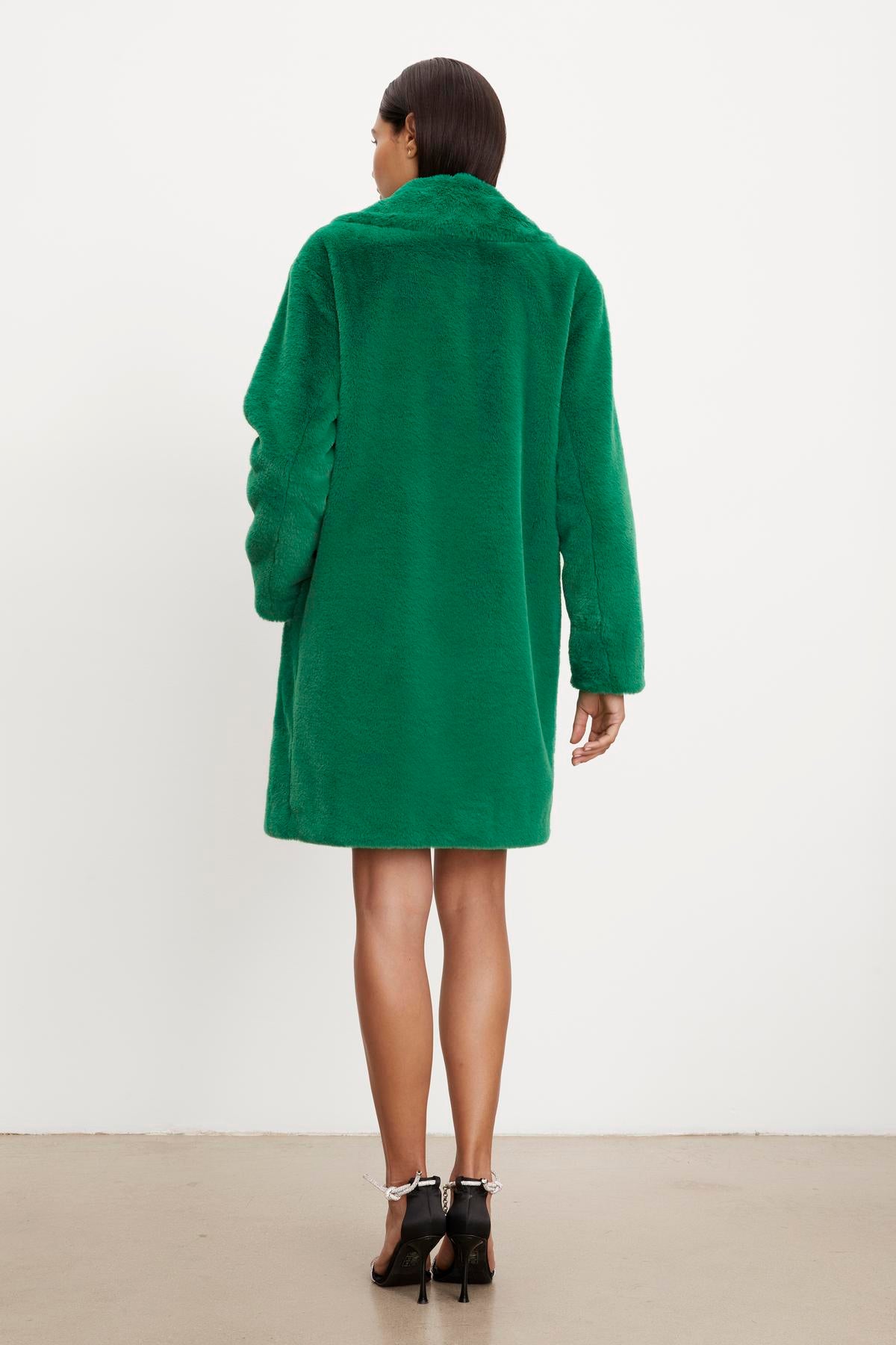 The silhouette of a woman in an EVALYN LUX FAUX FUR COAT by Velvet by Graham & Spencer.-35624128446657