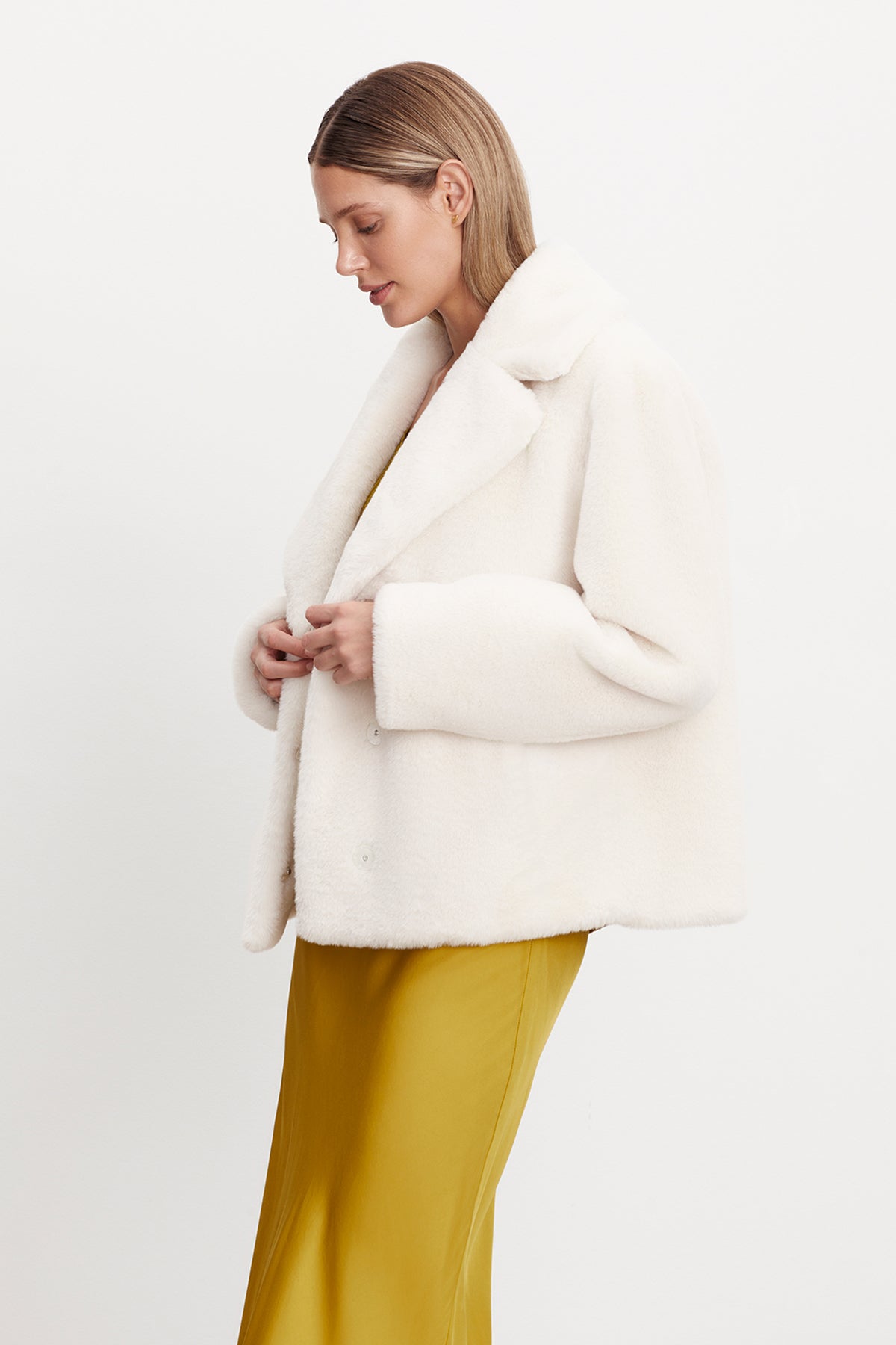   The model is wearing a white RAQUEL FAUX LUX FUR JACKET by Velvet by Graham & Spencer. 