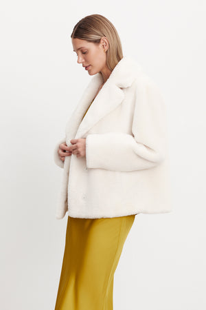 The model is wearing a white RAQUEL FAUX LUX FUR JACKET by Velvet by Graham & Spencer.