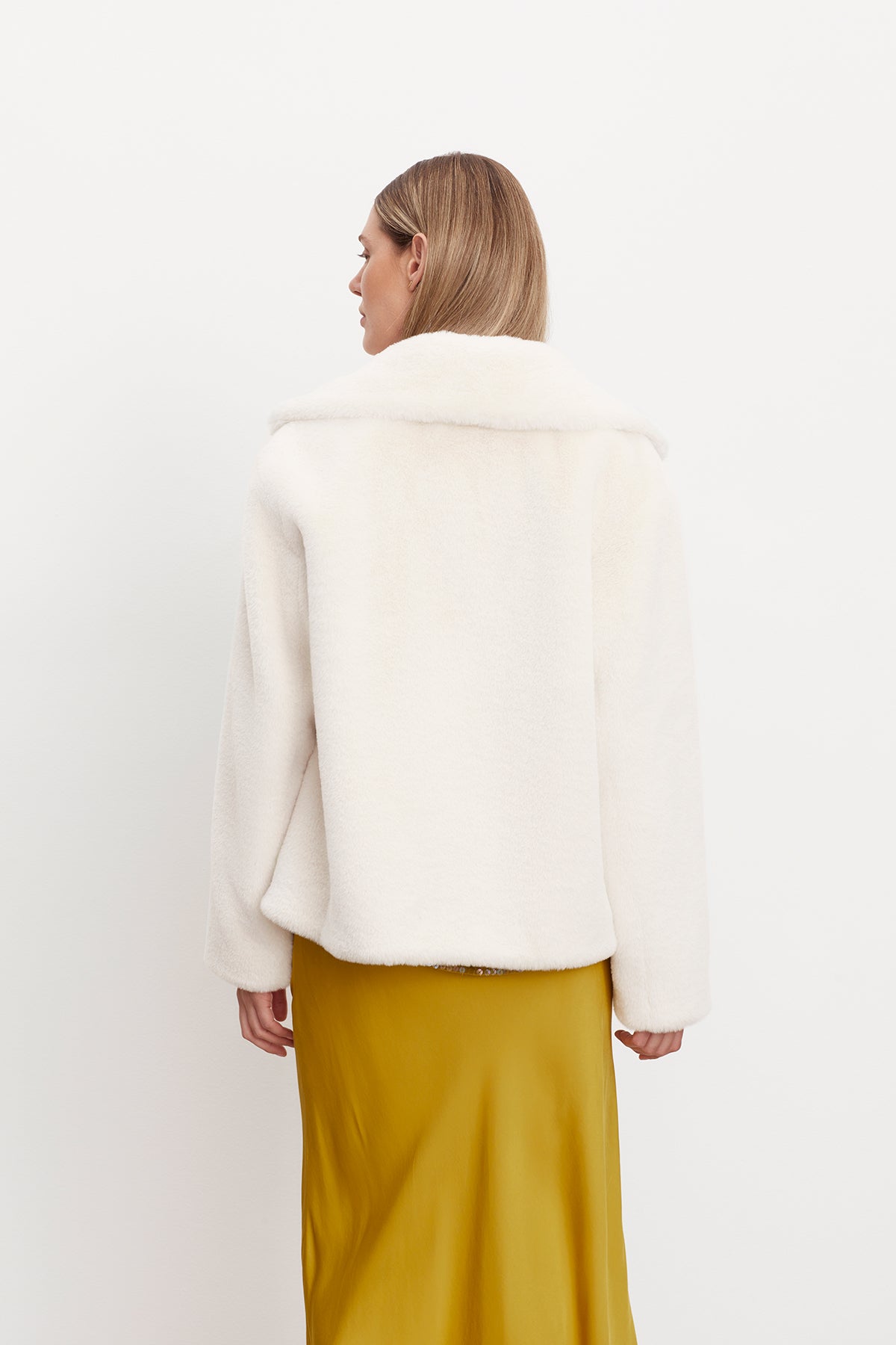   The back view of a woman wearing a white Velvet by Graham & Spencer RAQUEL FAUX LUX FUR JACKET. 