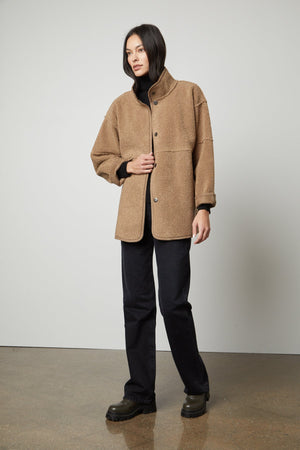 A woman wearing an ALBANY LUX SHERPA REVERSIBLE JACKET by Velvet by Graham & Spencer and black pants.