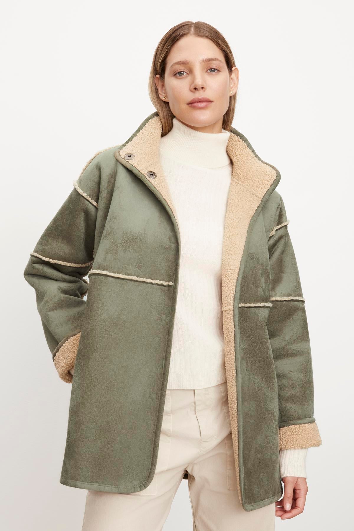  A woman wearing an Albany Lux Sherpa Reversible jacket by Velvet by Graham & Spencer with a faux sherpa collar. 