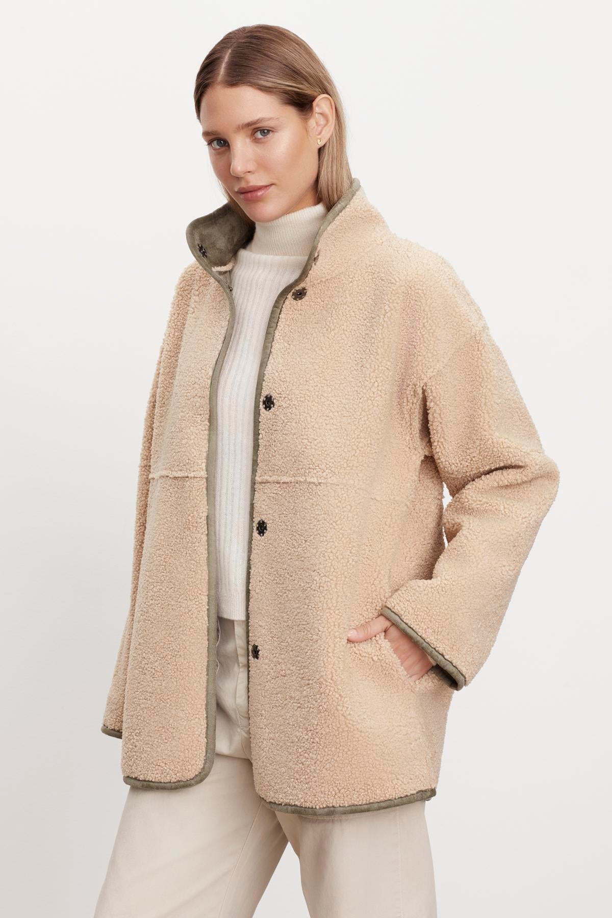 The model is wearing a beige ALBANY LUX SHERPA REVERSIBLE JACKET by Velvet by Graham & Spencer.-35582397087937