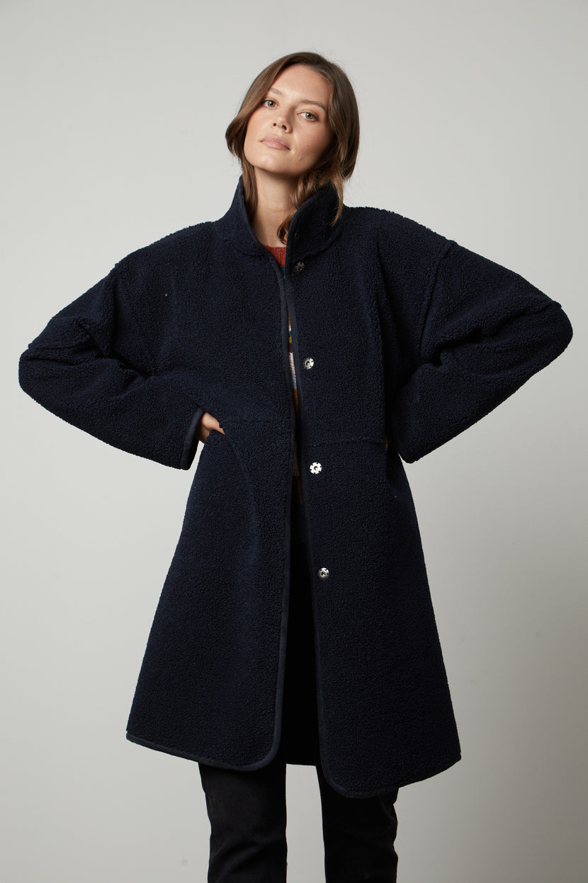 A woman wearing a Velvet by Graham & Spencer CARA LUX SHERPA REVERSIBLE JACKET and black pants.