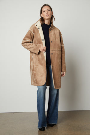 A woman wearing a CARA LUX SHERPA REVERSIBLE JACKET by Velvet by Graham & Spencer, tan coat and jeans.