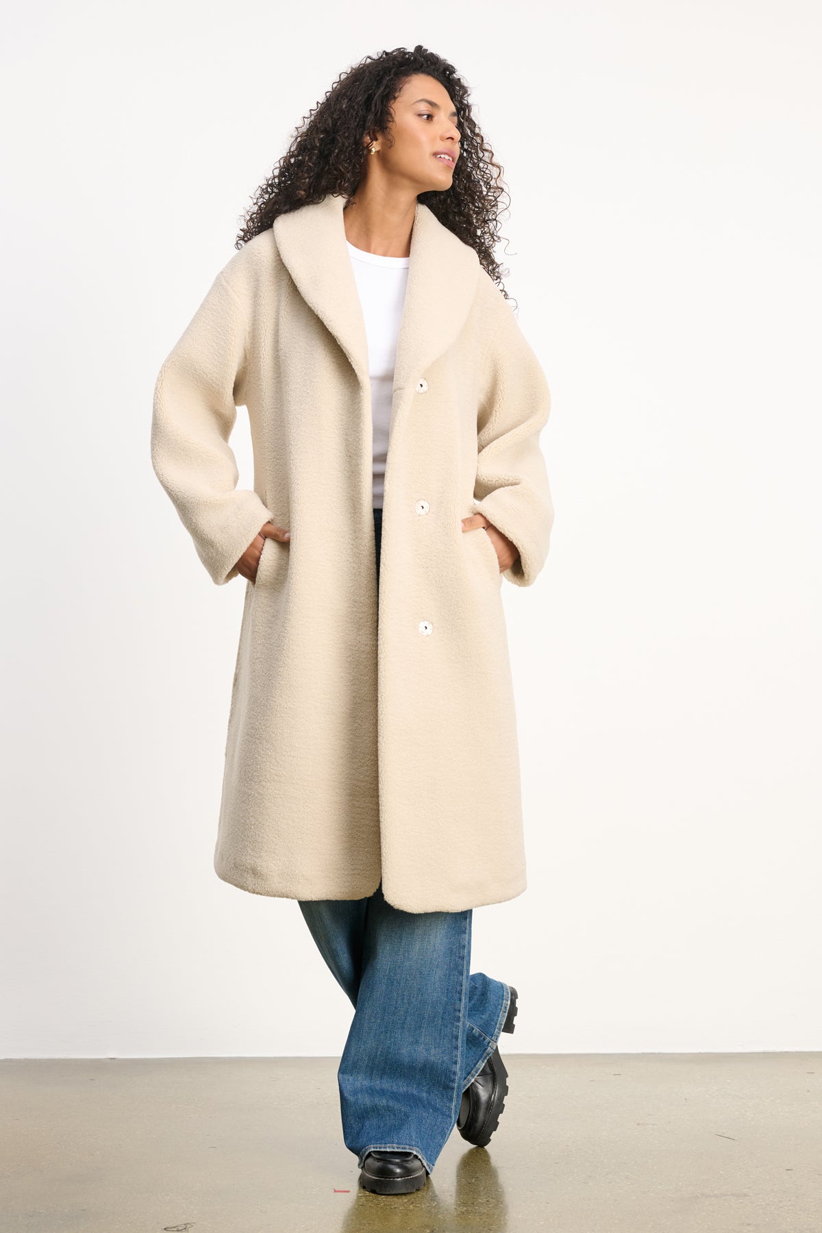 A person stands against a plain background wearing the ELEANOR SHERPA REVERSIBLE COAT by Velvet by Graham & Spencer, styled over a white top, blue jeans, and black shoes.-39838348181697