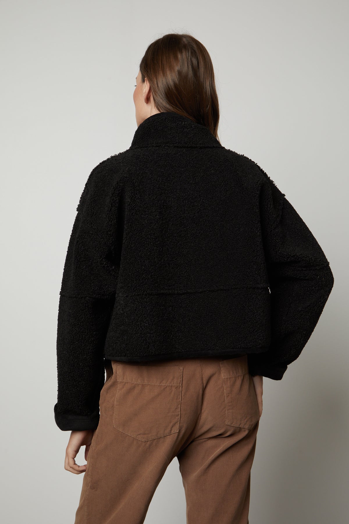 The back view of a woman wearing a Velvet by Graham & Spencer KELLY LUX SHERPA REVERSIBLE JACKET and brown pants.-26910369185985