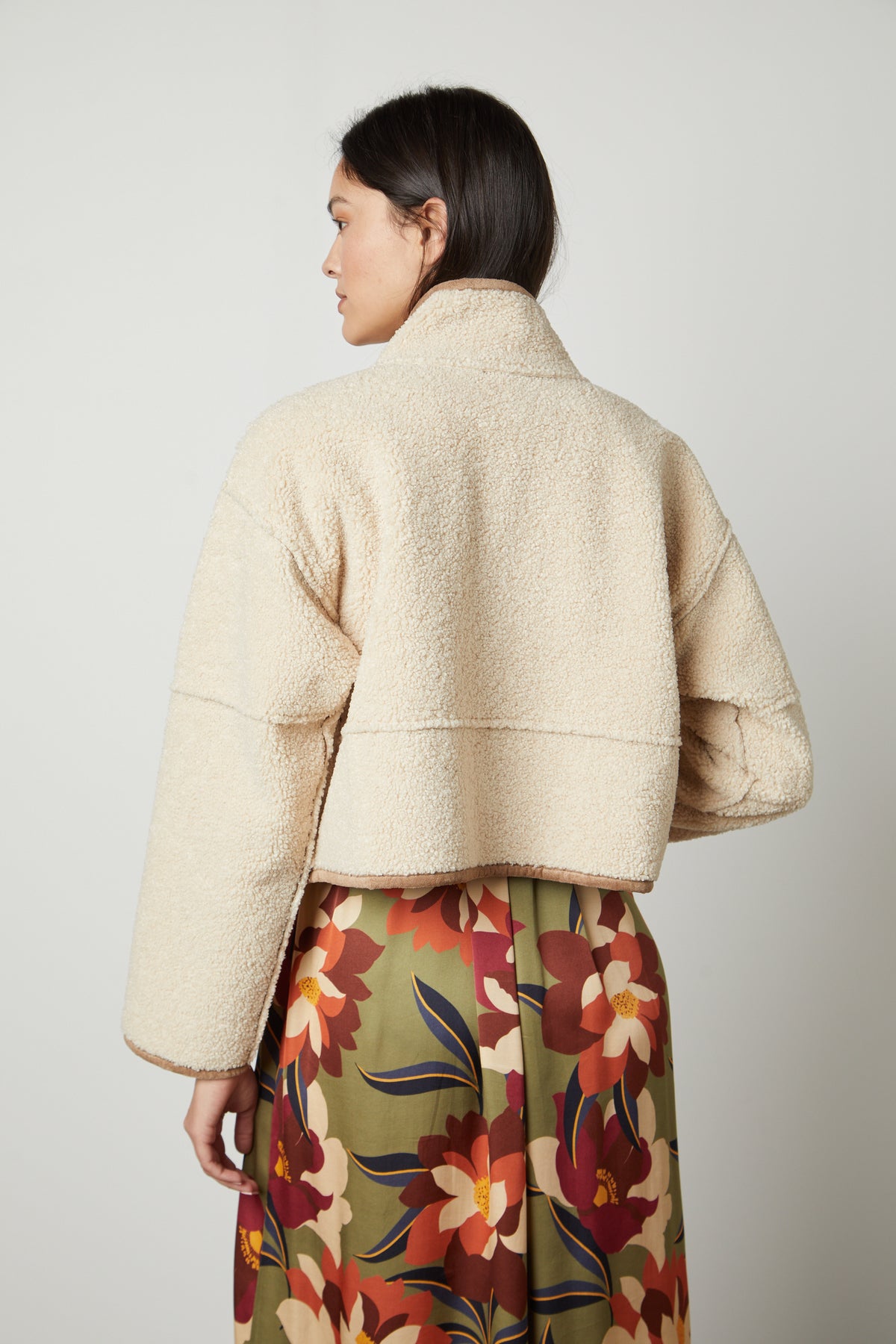 The back view of a person wearing a Velvet by Graham & Spencer KELLY LUX SHERPA REVERSIBLE JACKET and floral skirt.-26910374494401