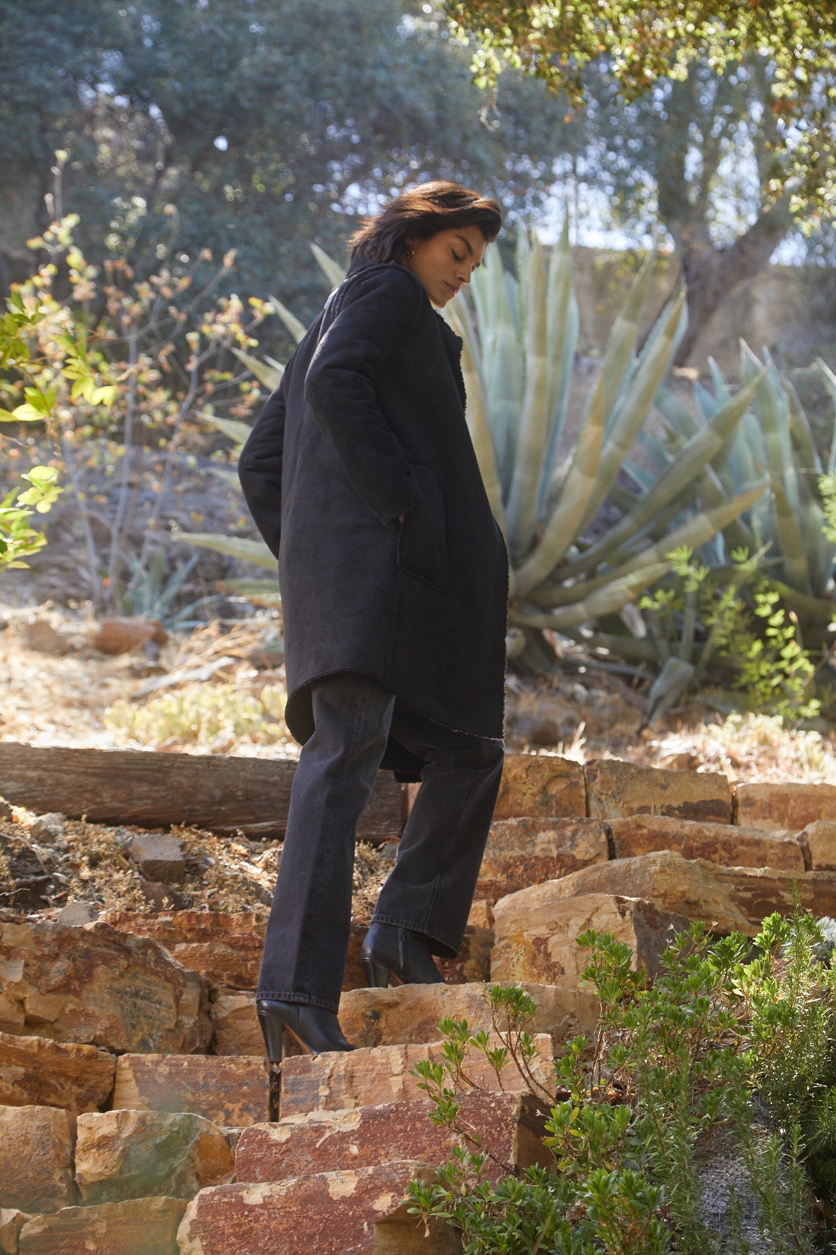   Model standing on steps outside wearing Mirabel Faux Lux Sherpa Reversible Coat styled  with black denim and black heels side 