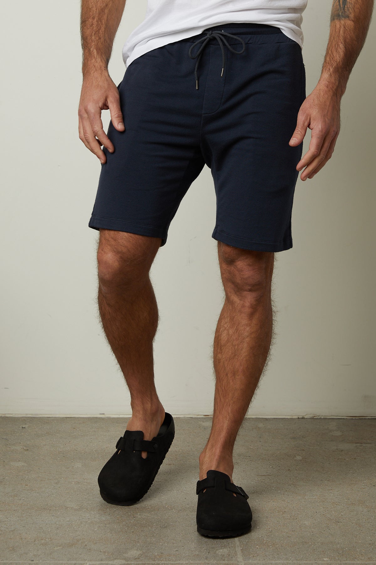   A man wearing a pair of ATLAS LUXE FLEECE DRAWSTRING SHORT by Velvet by Graham & Spencer and navy shorts for workouts. 
