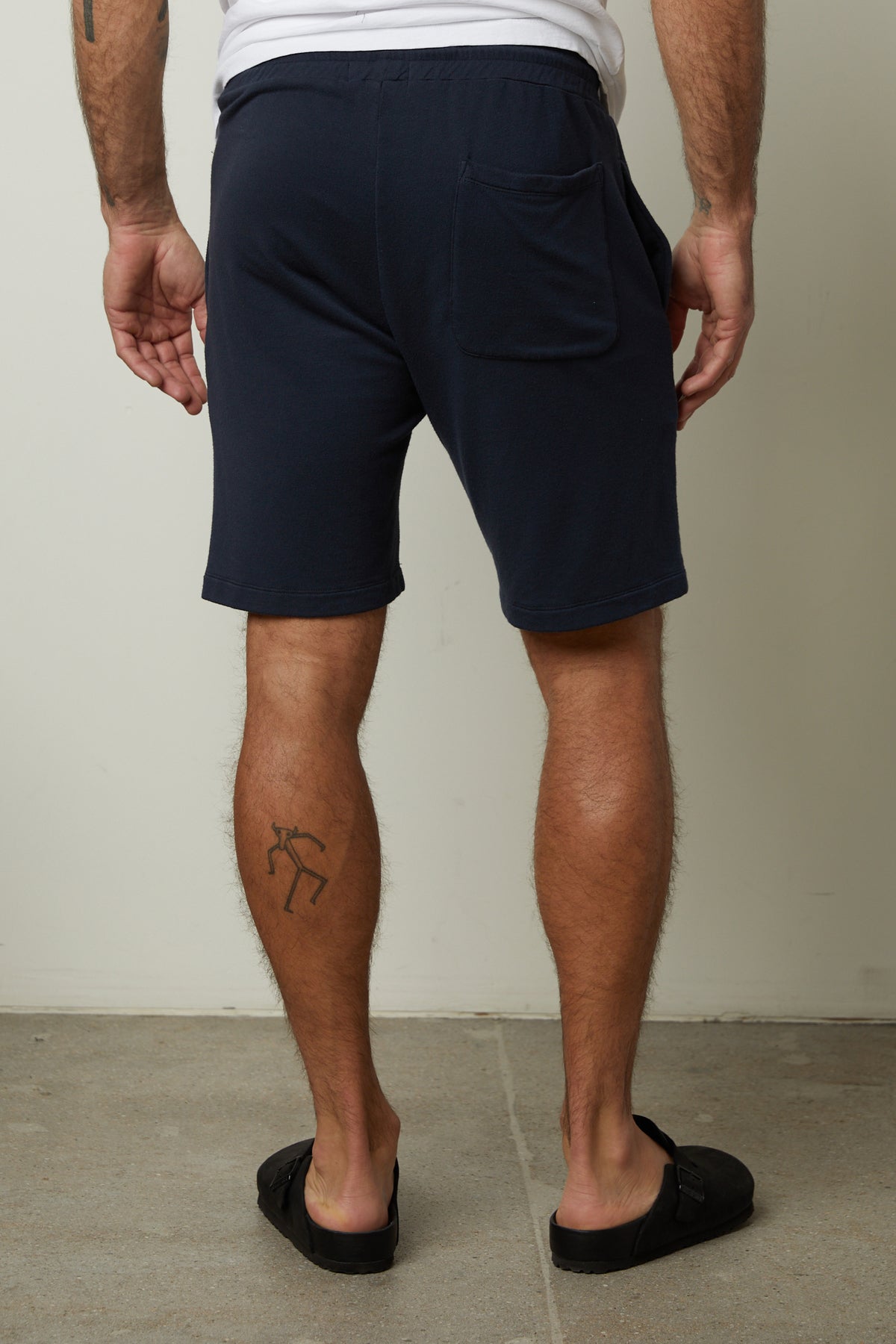   The back of a man wearing Velvet by Graham & Spencer's ATLAS LUXE FLEECE DRAWSTRING SHORT with tattoos. 
