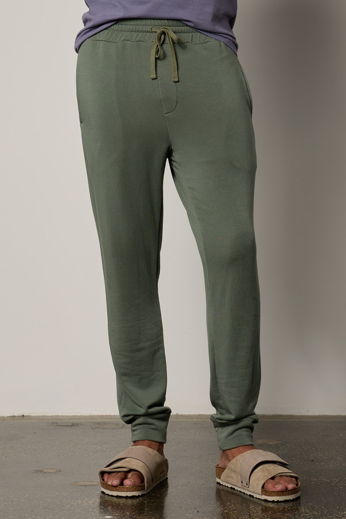   A man wearing a Green Velvet by Graham & Spencer Crosby Luxe Fleece Jogger and flip flops for workouts. 