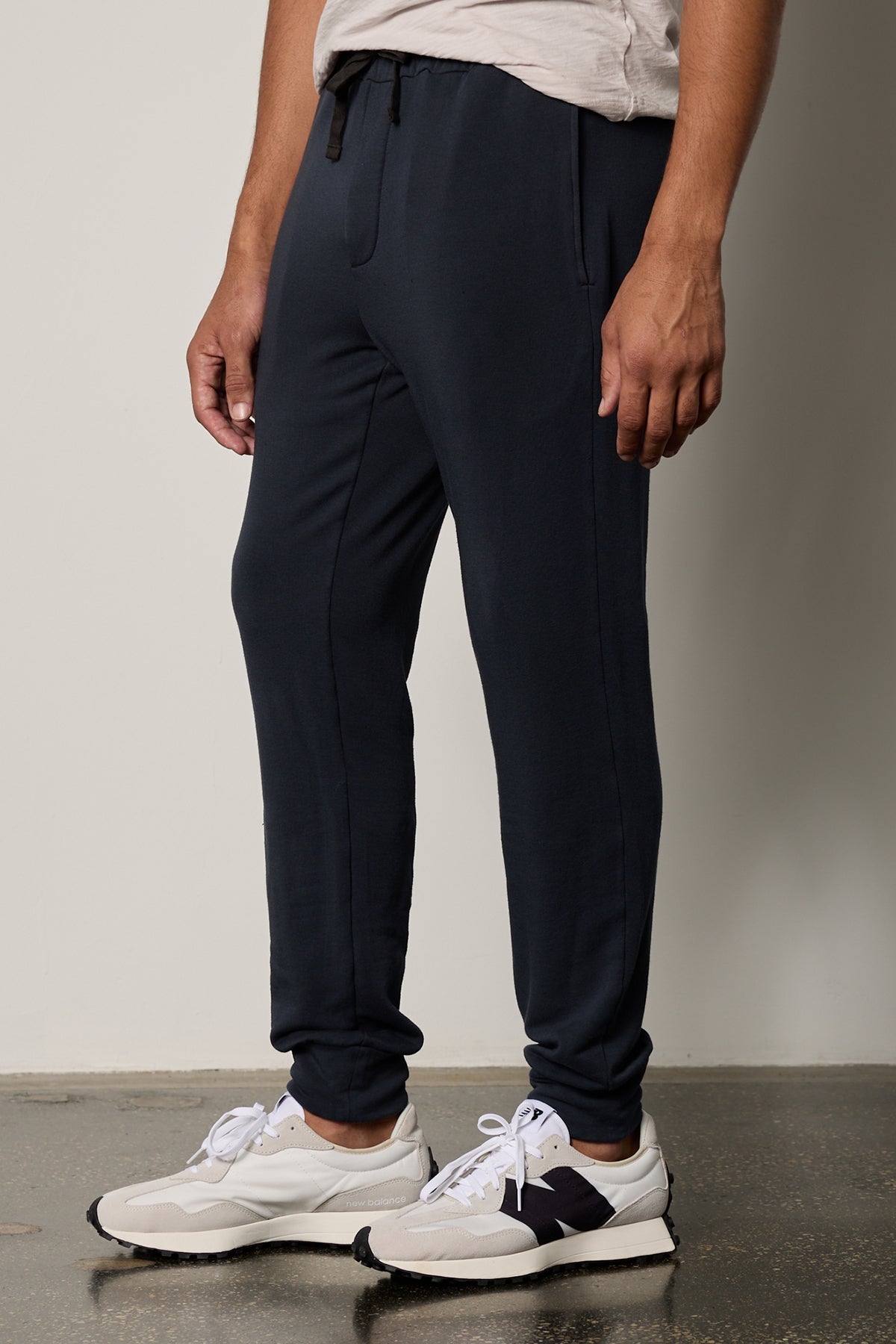 A man wearing Velvet by Graham & Spencer's CROSBY LUXE FLEECE JOGGER sweatpants and white sneakers, showcasing a tailored design and go-anywhere essential style.-26630189121729