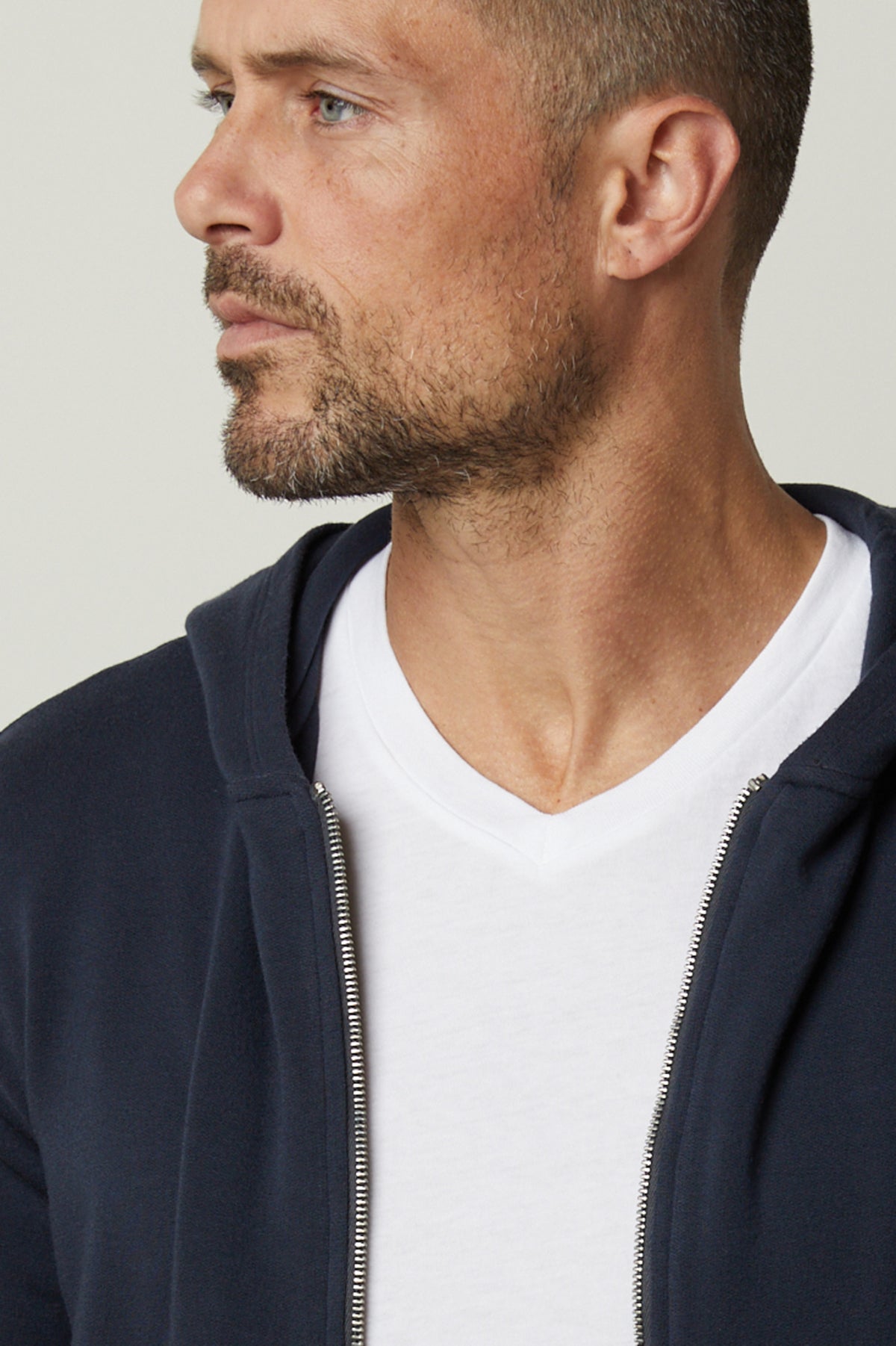 A man wearing a Velvet by Graham & Spencer navy RODAN LUXE FLEECE ZIP HOODIE and white t-shirt, showcasing the intricate fabrication details reminiscent of gym-class attire.-35662630125761