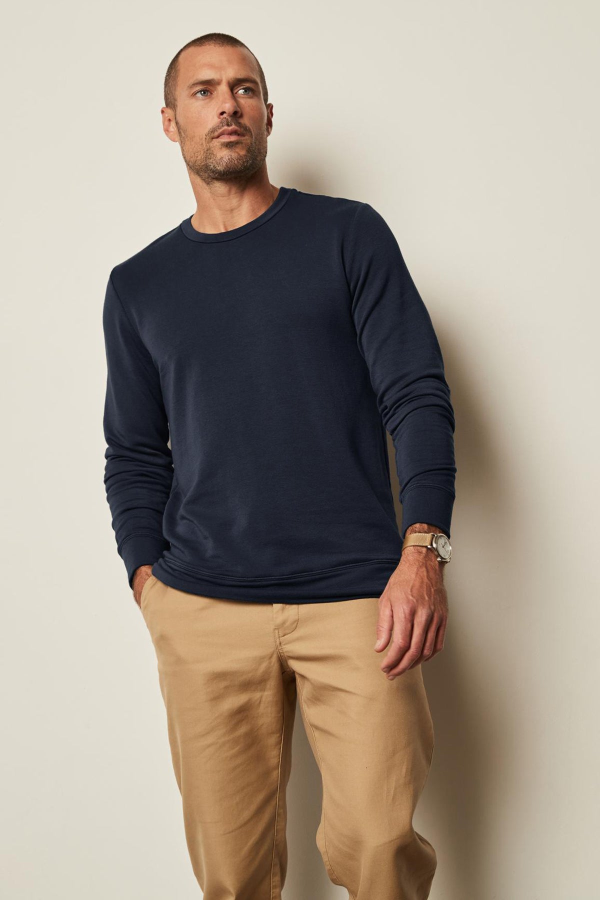  A man wearing a Velvet by Graham & Spencer SOREN LUXE FLEECE PULLOVER with a soft interior and tan pants. 