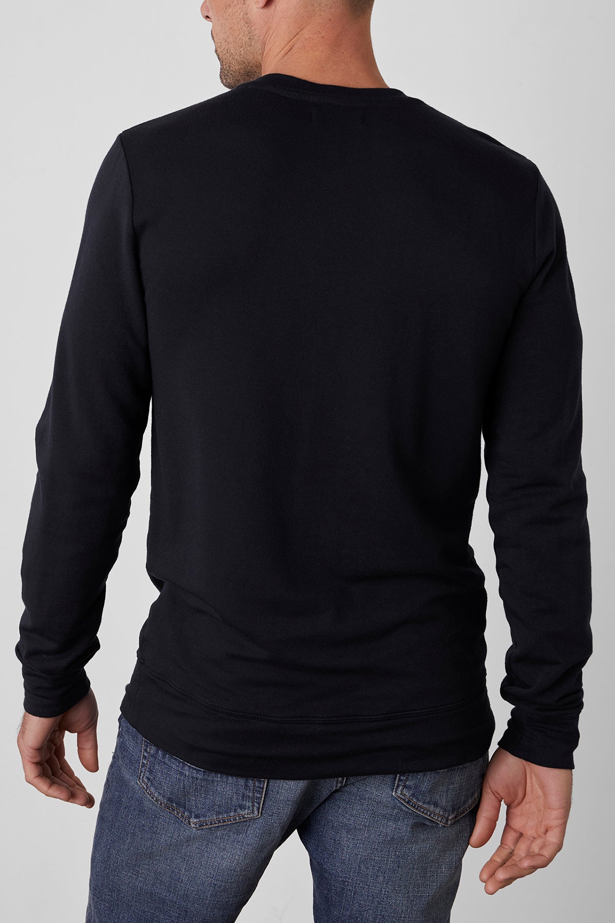   A man wearing a SOREN PULLOVER in cozy black from Velvet by Graham & Spencer and blue jeans, seen from the back. 