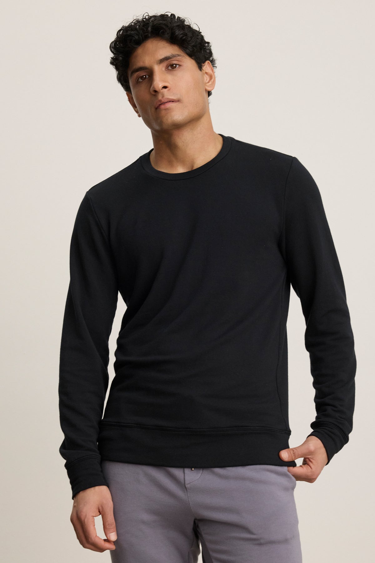 A man stands against a plain background wearing the SOREN PULLOVER by Velvet by Graham & Spencer and light gray pants, looking straight at the camera with a neutral expression.-39841106624705